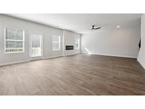 Bright, open-concept living room with hardwood floors, a fireplace, and ample natural light from large windows at 358 Orwell Dr, Social Circle, GA 30025