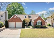 Charming brick home with a well-manicured lawn, mature trees, and an attached two-car garage at 1483 Chamirey Sw Dr, Marietta, GA 30008