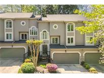 Charming townhome featuring a garage, front garden, and gray stucco exterior at 1209 Brookhaven Woods Ne Ct, Brookhaven, GA 30319