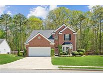 Charming brick home with a well-manicured lawn, two-car garage, and lush landscaping at 2523 Bancroft Way, Buford, GA 30519