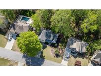 An aerial view shows the house surrounded by trees, lawn, driveway and nearby houses with a swimming pool at 4414 Aldenham N Way, Suwanee, GA 30024