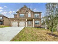 Inviting two-story brick home showcasing a two-car garage and well-manicured front lawn at 8045 Hillside Climb Way, Snellville, GA 30039