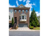 Charming two-story brick townhome with a one-car garage and landscaped front yard at 2171 W Village Se Ln, Smyrna, GA 30080