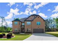 Elegant two-story brick home featuring a manicured lawn, attached garage, and driveway at 404 Prague Way, Hampton, GA 30228