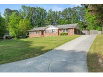 Charming brick home featuring a long driveway, lush lawn and mature trees at 3127 Hidden Forest Dr, Snellville, GA 30078
