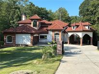 Stunning home featuring a tile roof, arched entryway, and lush landscaping at 725 Links View Dr, Sugar Hill, GA 30518