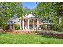 Beautiful brick home featuring a stately facade with large columns, lush landscaping, and a well-manicured lawn at 2000 Old Dominion Rd, Atlanta, GA 30350