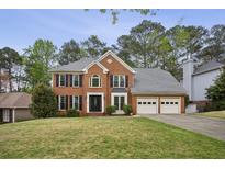Traditional brick home featuring a well-manicured lawn, a two-car garage, and classic architectural details at 4284 Windy Gap Nw Ct, Kennesaw, GA 30144