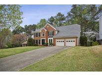 Beautiful brick home with a two-car garage and long driveway, surrounded by lush trees and greenery at 4284 Windy Gap Nw Ct, Kennesaw, GA 30144