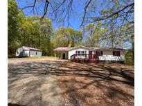Charming single-story home with white siding, a cozy front porch, and a detached garage at 5130 English Dr, Cumming, GA 30041