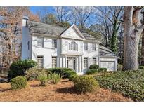 Beautiful two-story home featuring a white brick facade, landscaped front yard, and attached two-car garage at 2125 Fairfax Dr, Alpharetta, GA 30009