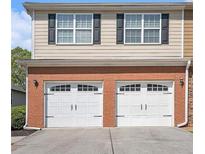 Two-car garage with brick facade and black window shutters for a traditional home design at 1960 Dakota Nw Dr, Acworth, GA 30101