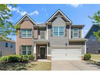 Charming two-story home with brick and shingle siding, a well-manicured lawn, and an attached two-car garage at 5750 Palmtree Pass, Cumming, GA 30040