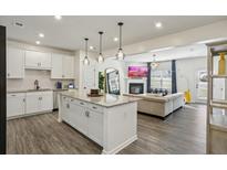 Open-concept living room with white cabinets, granite counters, and island with pendant lighting, flowing into a cozy living area at 375 Crider Ct, Woodstock, GA 30188