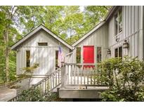 Charming home featuring a bright red door, gray siding, and an inviting porch, perfect for enjoying the surrounding greenery at 7470 Princeton Trce, Sandy Springs, GA 30328