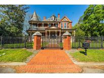Stunning brick Victorian home with a turret, large porch, and wrought iron fence and gate with brick pillars at 3593 Hemphill St, Atlanta, GA 30337
