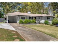 Charming single-story home with a manicured front lawn and attached carport in a wooded neighborhood at 2123 Juanita St, Decatur, GA 30032