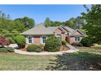 Charming single-story brick home featuring manicured landscaping, a curved walkway, and a well-maintained lawn at 3925 Waterford Dr, Suwanee, GA 30024