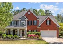 Charming two-story home with brick and gray siding, manicured lawn, and a welcoming front porch at 4013 Suwanee Place Dr, Suwanee, GA 30024
