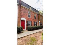 Charming two-story brick townhouse featuring a red door and lush green landscaping at 115 Winding River Dr # B, Atlanta, GA 30350