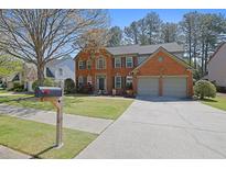 Charming two-story red brick home featuring an attached two-car garage and well-maintained landscaping at 302 Wickley Way, Woodstock, GA 30188