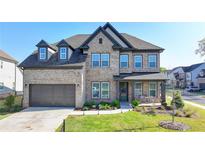 Beautiful two-story brick home featuring a two-car garage, a covered front porch, and manicured landscaping at 4409 Encore Park Lane, Duluth, GA 30097