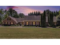 Charming brick home with well-manicured lawn, mature trees, and dusk sky for a warm, inviting feel at 1935 Northbrooke Ln, Atlanta, GA 30338