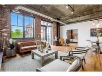 Bright living room features exposed brick, concrete ceilings, stylish furniture, and large windows at 3235 Roswell Ne Rd # 721, Atlanta, GA 30305