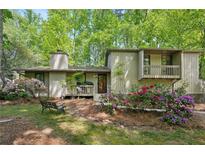 Inviting front exterior featuring a quaint porch, lush landscaping, and natural setting at 4553 Pond Ln, Marietta, GA 30062