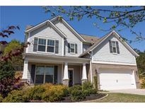 Charming two-story home featuring a brick-accented garage, gray siding, and a well-manicured front yard with mature landscaping at 2034 W Hampton Dr, Canton, GA 30115