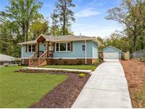 Charming blue house with a well-manicured lawn, fresh mulch, and a spacious driveway leading to a detached garage at 2374 Marion Cir, Decatur, GA 30032