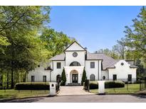Stunning white home with manicured landscaping and black trim, enhanced by a wrought iron fence and mature trees at 725 Riley Pl, Atlanta, GA 30327