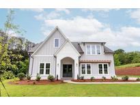Charming two-story home featuring a white brick archway, large windows, and a well-manicured lawn at 6565 Rhett Run, Cumming, GA 30028