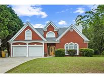 Charming brick home with a two-car garage and a well-manicured front lawn under a partly cloudy sky at 4505 Lakefield Bnd, Berkeley Lake, GA 30096