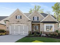 Charming, light brick home featuring a two-car garage and a beautifully landscaped front yard at 3825 Raeburn Rd, Cumming, GA 30028