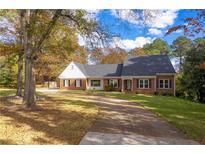 Charming brick home with black shutters, mature trees, and a curved driveway at 2636 Harvest Se Dr, Conyers, GA 30013