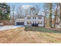 Charming two-story home with a well-maintained lawn, a black front porch, and a two-car garage at 5465 N Fork Sw Dr, Lilburn, GA 30047
