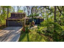 Charming brown home with a lush front yard and a two-car garage surrounded by mature trees at 859 Bridgewater Ct, Stone Mountain, GA 30088