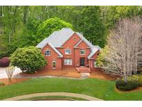 Elegant two-story red brick home with a well-manicured lawn and lush, mature landscaping at 221 Streamside Ct, Lilburn, GA 30047