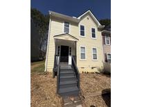 Charming two-story home with pale yellow siding, black front door, and inviting covered porch at 4049 Heritage Valley Ct, Norcross, GA 30093