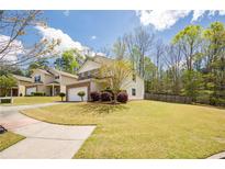 Charming two-story home with a well-manicured lawn, attached garage, and beautiful landscaping at 6884 Barker Station Walk, Sugar Hill, GA 30518