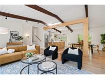 Bright living room with wood beam ceiling, modern furniture, and an open floor plan to the kitchen at 1690 Cotswold Ne Dr, Brookhaven, GA 30319