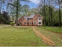 Beautiful brick home featuring a manicured lawn, mature trees and classic architectural details at 9174 Retreat Pass, Jonesboro, GA 30236