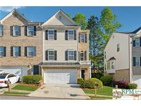 Charming townhouse with a two-car garage, well-maintained lawn, and a mix of brick and siding accents at 420 Eagle Tiff Dr, Sugar Hill, GA 30518