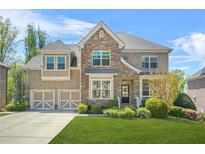 Charming two-story brick and stone home with a well-manicured lawn and a two-car garage at 5895 Springbox Dr, Suwanee, GA 30024