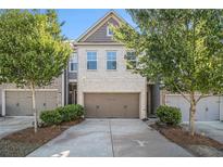 Charming townhome featuring a two-car garage and a welcoming brick facade surrounded by lush trees at 2721 Kemp Sw Ct, Conyers, GA 30094