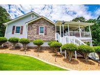 Charming home featuring a stone facade, a welcoming front porch, and meticulously manicured landscaping at 84 Ledbetter Rd, Villa Rica, GA 30180