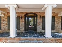 Elegant front entryway with a stylish door, decorative columns, and a brick facade at 6141 Windsong Way, Smoke Rise, GA 30087