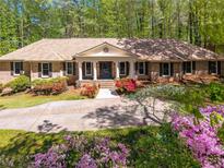 Charming one story home with a brick exterior, mature trees, and a well manicured lawn at 6141 Windsong Way, Smoke Rise, GA 30087