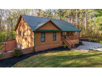 Charming house featuring wood siding, a green metal roof, front porch, and a well-manicured lawn at 5070 Smithfield Rd, Bowdon, GA 30108